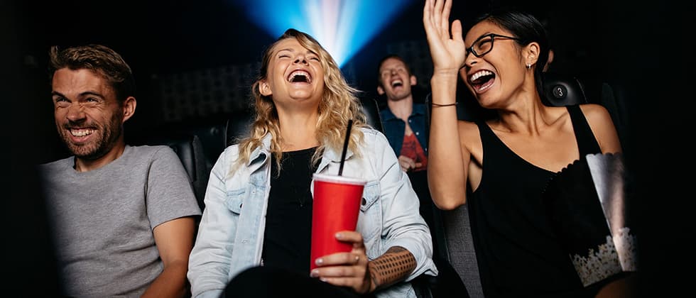 Friends watching a show in a theater and laughing