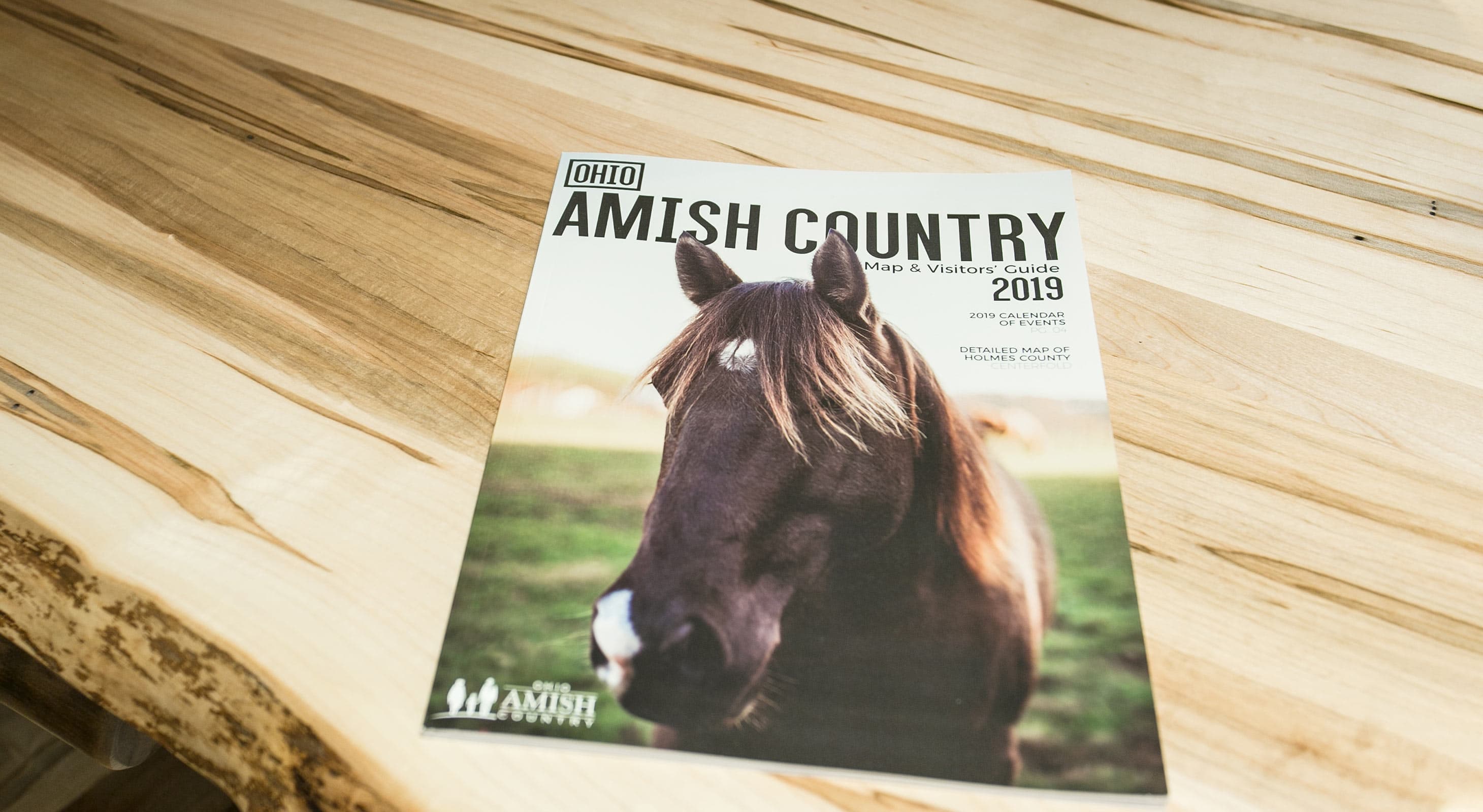 Cover of Ohio Amish Country Map & Visitors Guide 2019 - sitting on wood table