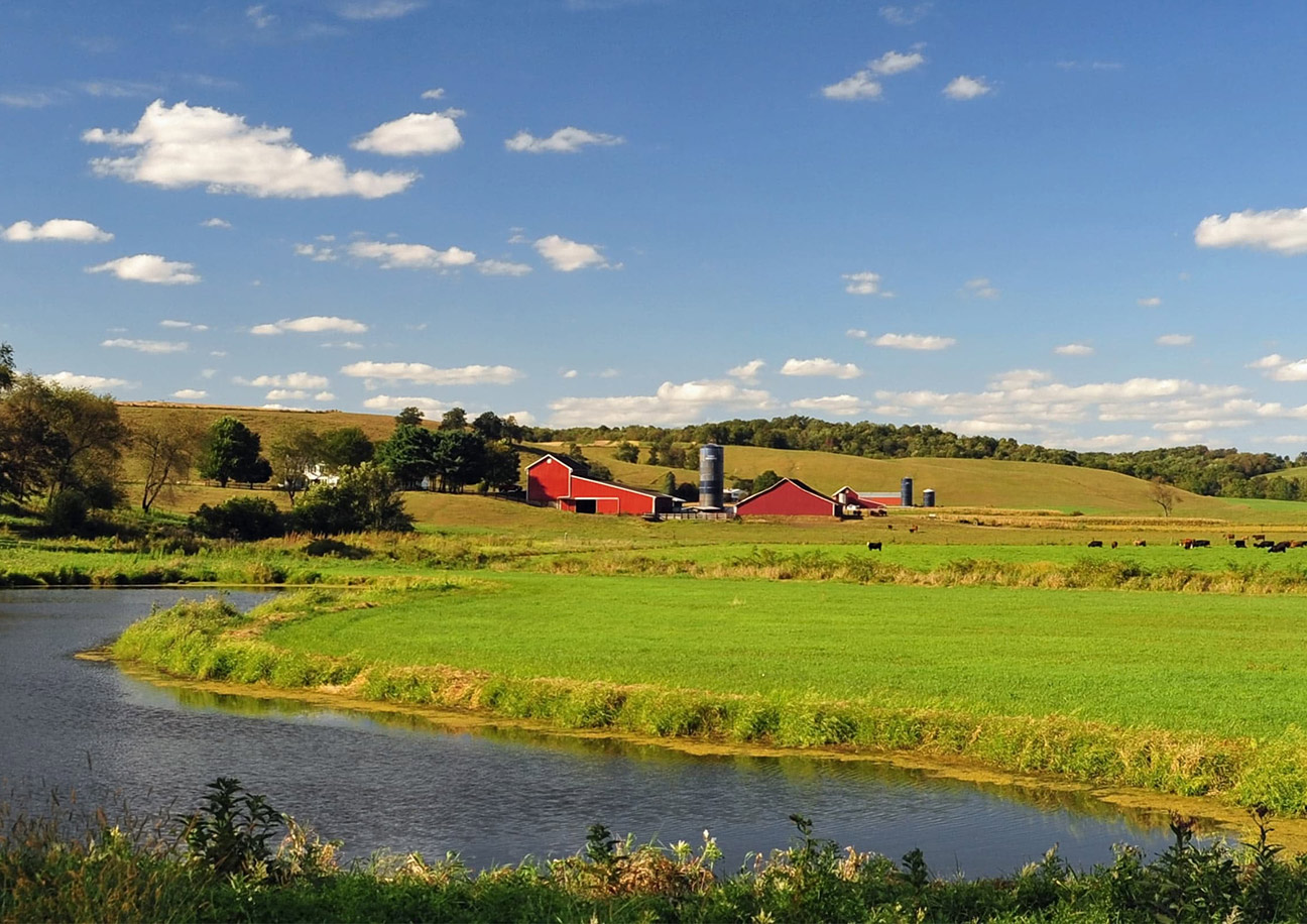 red barn in a field by a river