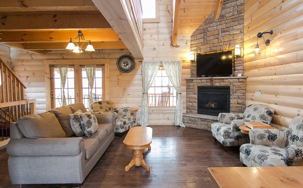 Living Room with couch, 2 chairs, and rock fireplace in Hummingbird Haven