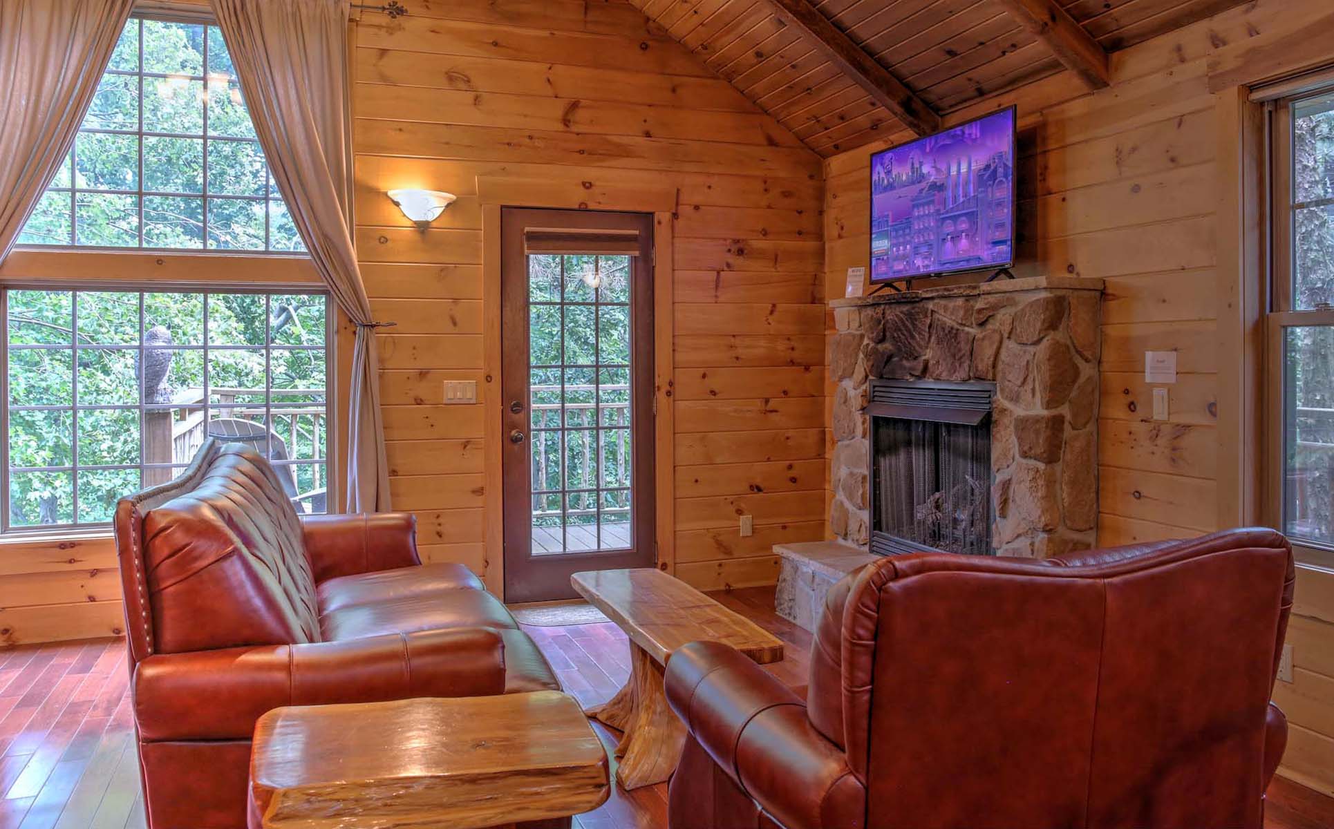 Interior of Treehouse with bed, couch, stone fireplace, and TV