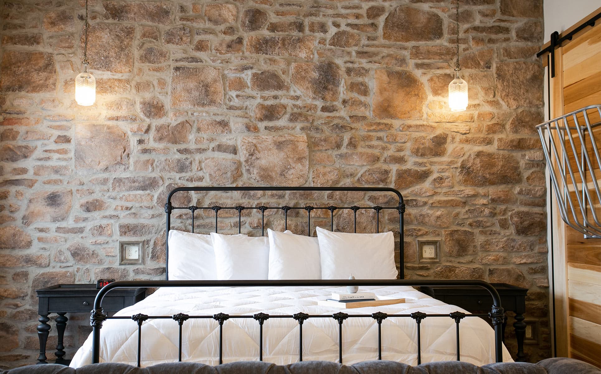 King bed in front of stone wall with pendant lights