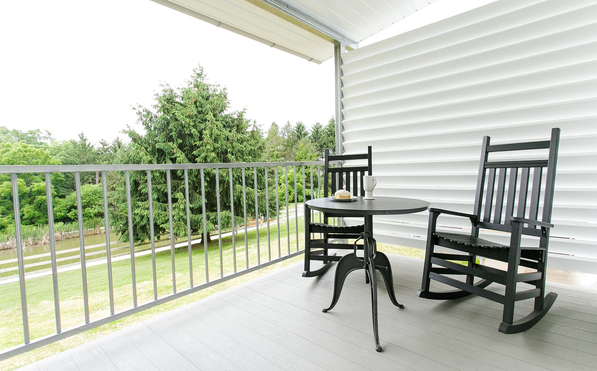 Covered porch with rocking chairs overlooking pond