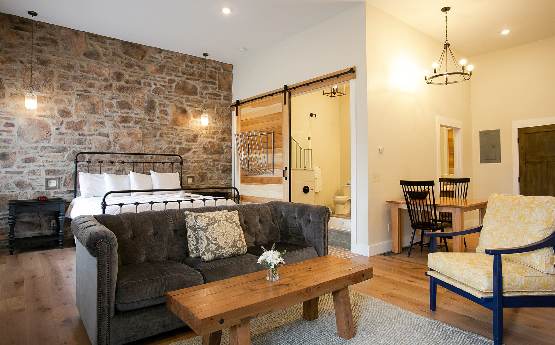 Parlor Suite bed with stone wall, couch, chair, dining table, and bathroom