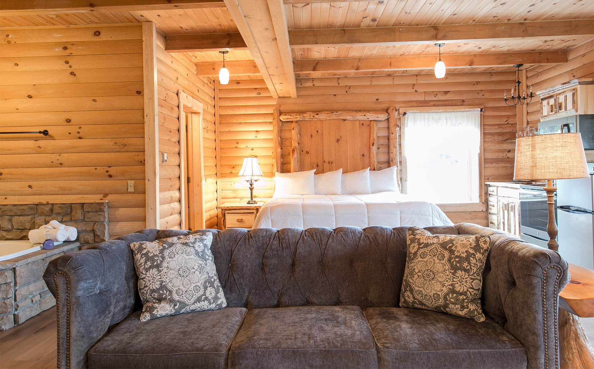 Grey couch with bed and kitchen in background